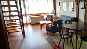 A room with a dining table, chairs, a sofa, a lamp, and a radiator. - Vacation apartment Lärch 17c (Siegsdorf)