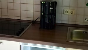 A kitchen with white cabinets, a coffee maker, and a dishwasher. - Vacation apartment Lärch 17c (Siegsdorf)