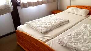 A double bed with a wooden headboard, white bedding, and a window with curtains. - Vacation apartment Lärch 17c (Siegsdorf)