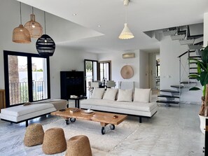 Ein geräumiges Wohnzimmer mit einer Couch, einem Couchtisch und Korbsesseln.