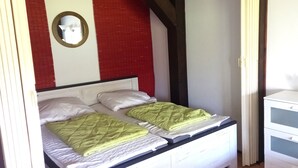 A bedroom with two beds, a mirror, and a dresser. - Vacation apartment Iris 5 (Siegsdorf)