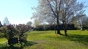 A grassy park with trees and a building in the background. - Vacation apartment Glock 6 (Siegsdorf)