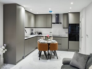 Una cocina moderna con armarios grises, una mesa de comedor con dos sillas y un refrigerador.