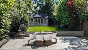A patio with a table and chairs, a birdcage, and a house in the background. - Apartment 2 - UK51647 (Maldon)