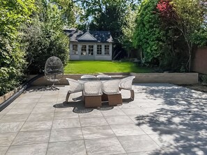 A patio with a table and chairs, a birdcage, and a house in the background.