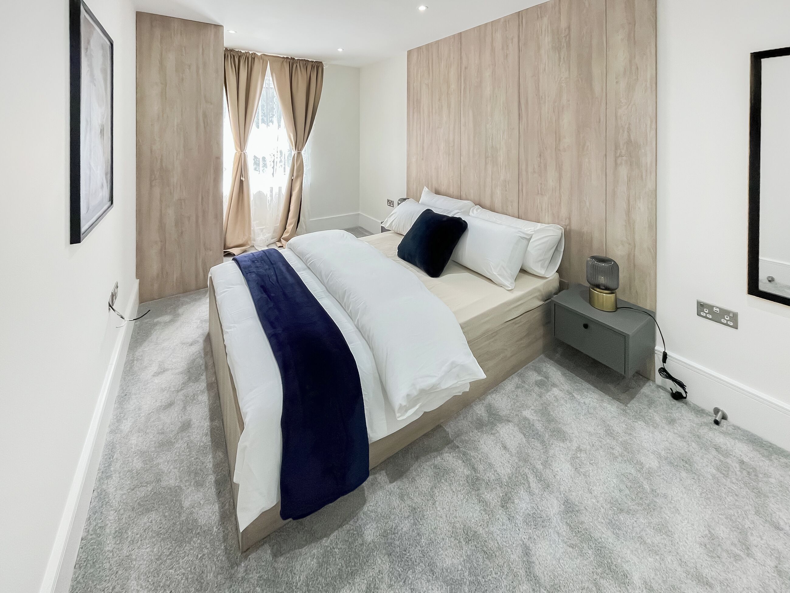 Un dormitorio moderno con cama, mesita de noche y velador.