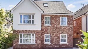 A two-story house with a brick facade, multiple windows, and a visible garage door.
