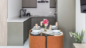 A compact kitchen with modern appliances, a dining area with a round table, and a small decorative plant.