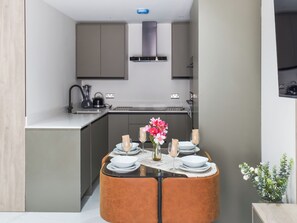 Una cocina compacta con electrodomésticos modernos, un comedor con una mesa redonda y una pequeña planta decorativa.