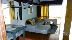 A living room with a sofa, a dining table, and a small side table.