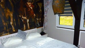 A bedroom with a bed, a window, and a wall mural.