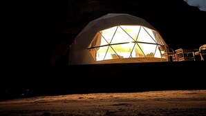 A geodesic dome structure with a large window, interior seating, and a view of the landscape. - Magic rum hussen Luxury (Wadi Rum Village)