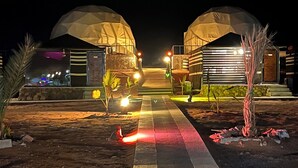 Une vue nocturne d’un bâtiment doté de deux grandes structures en forme de dôme.