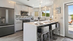 A modern kitchen with a central island, stainless steel appliances, and pendant lighting.