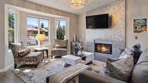 A living room with a fireplace, patterned chairs, a sofa, and a television.