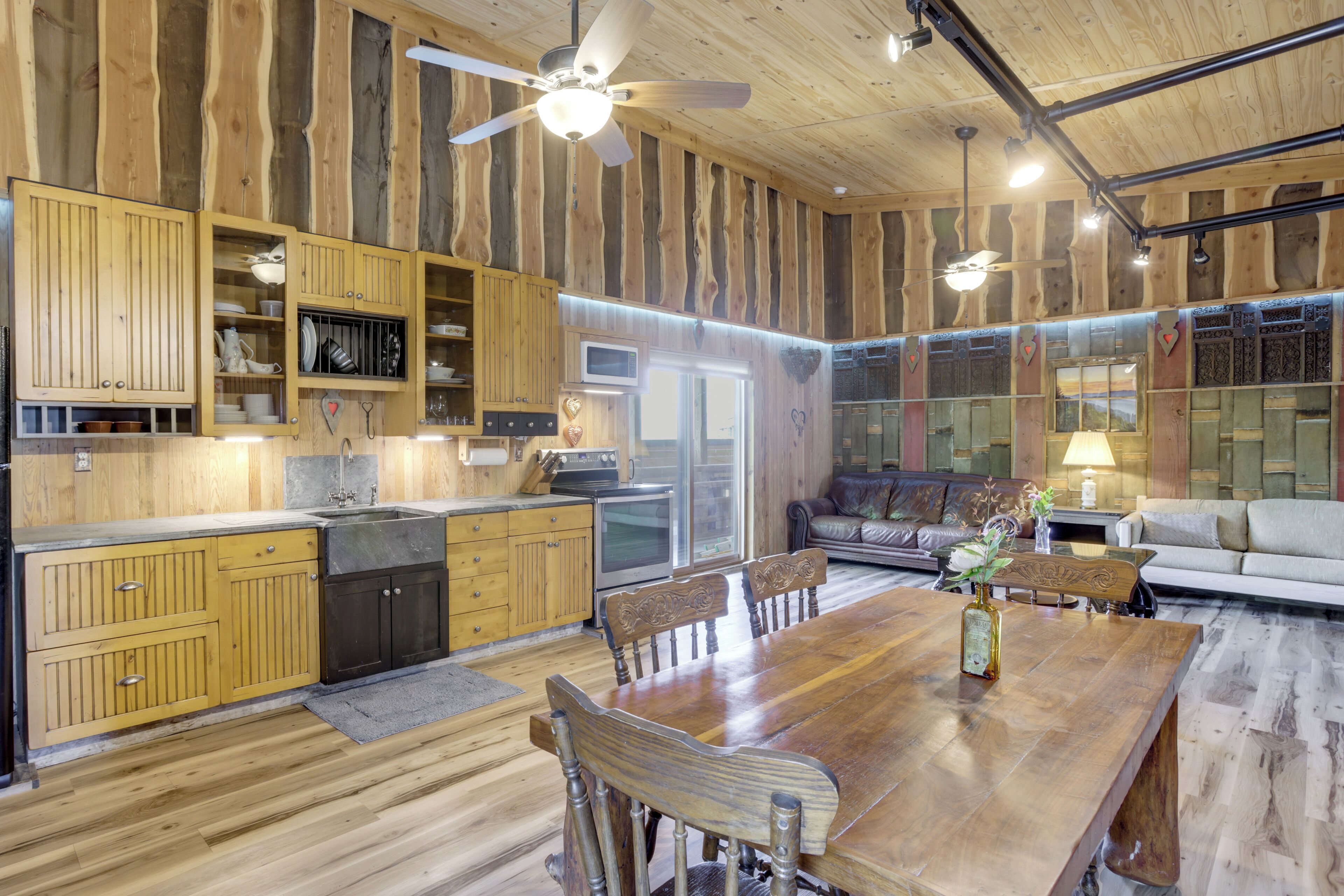 Una cocina amplia con armarios de madera, un comedor con una gran mesa de madera y una sala de estar con un sofá y una televisión.