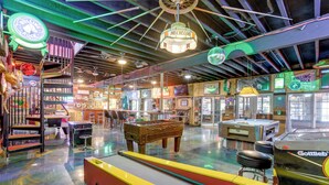 A retro-themed arcade with neon signs, a foosball table, and various gaming machines. - Hike, Soak + Play: Rustic Maysville Escape! (Maysville)