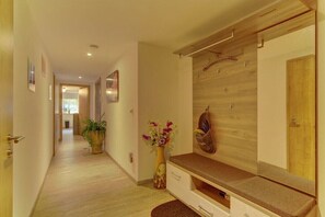 A hallway with a wooden bench, a vase with flowers, and a wooden wall with a coat rack. - Holiday apartment in Mauth with swimming pool (Mauth)