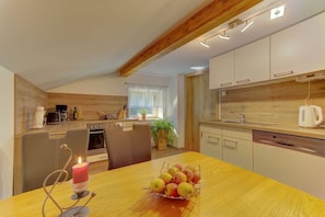 A modern kitchen with wooden cabinets, a dining table with apples, and a candle. - Holiday apartment in Mauth with swimming pool (Mauth)