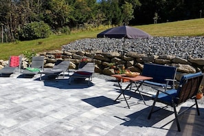 A patio with lounge chairs, a table, and an umbrella. - Holiday apartment in Mauth with swimming pool (Mauth)