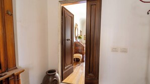A hallway with a wooden door, a small rug, and a vase. - Casa dello Scrittore (Florence)
