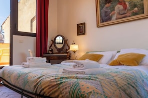 A hotel room with a bed, a bedside table with a lamp, a mirror, and a painting on the wall. - Casa dello Scrittore (Florence)