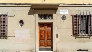A building with a wooden double door, a sign above the door, and barred windows on either side. - Casa dello Scrittore (Florence)