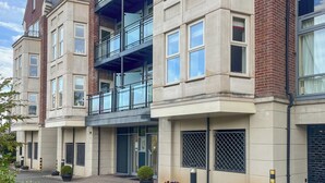 Um edifício de vários andares com arquitetura moderna, apresentando uma combinação de fachadas de tijolo e concreto, janelas amplas e uma varanda bem destacada.