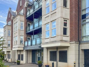 Ein mehrstöckiges Gebäude mit moderner Architektur, das Ziegel- und Betonfassaden, große Fenster und einen markanten Balkonbereich kombiniert.