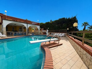 A swimming pool with a diving board, lounge chairs, and a covered patio area. - Villa in Marina Di Ragusa with 5 bedrooms sleeps 10 (Marina Di Ragusa)