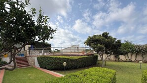 Ein angelegter Garten mit gepflegtem Rasen, einer Hecke und einem gepflasterten Weg, der zu einem Gebäude im modernen architektonischen Stil führt.