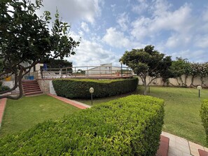 A landscaped garden with a well-maintained lawn, a hedge, and a paved walkway leading to a building with a modern architectural style. - Villa in Marina Di Ragusa with 5 bedrooms sleeps 10 (Marina Di Ragusa)