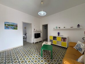 A living room with a television, a green chair, a yellow bookshelf, and a patterned floor. - Villa in Marina Di Ragusa with 5 bedrooms sleeps 10 (Marina Di Ragusa)