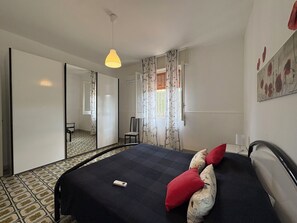 A bedroom with a bed, a chair, a desk, a mirror, and a window with curtains. - Villa in Marina Di Ragusa with 5 bedrooms sleeps 10 (Marina Di Ragusa)