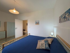 Ein Schlafzimmer mit einem Bett, einem Nachttisch, einer Lampe, einem Gemälde und einem Kleiderschrank.