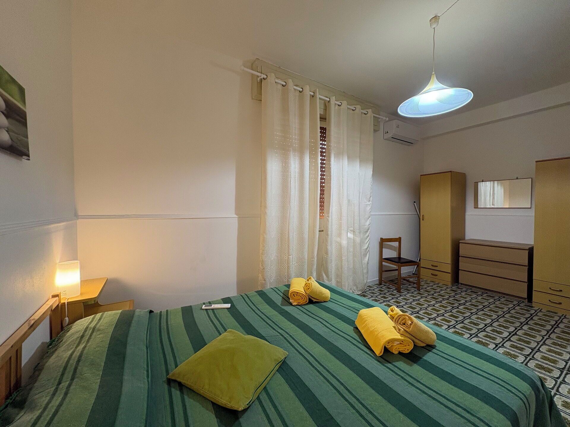 A hotel room with a bed, a chair, a desk, and a wardrobe.