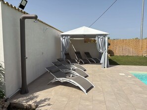 A poolside area with lounge chairs and a covered seating area.