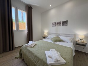 A bedroom with a bed, two bedside tables, a window with curtains, and wall art.