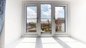 Ein Zimmer mit großem Fenster und Blick auf eine Wohngegend.