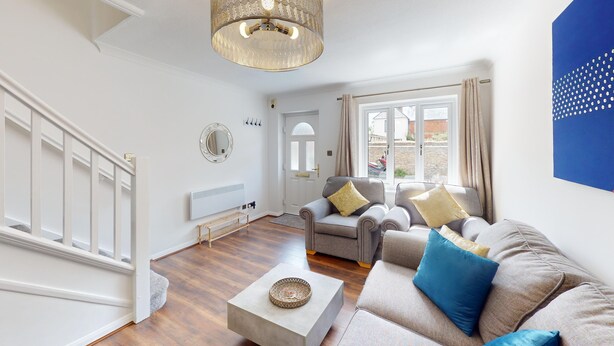 A living room with a sofa, a coffee table, a hanging light fixture, a radiator, and a door. - Buckland Mews - sleeps 4 guests  in 2 bedrooms (Abingdon)
