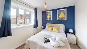 A hotel room with a bed, two bedside tables, a window with curtains, and two wall-mounted pictures. - Buckland Mews - sleeps 4 guests  in 2 bedrooms (Abingdon)