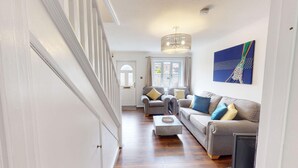 A modern living room with a staircase, a chandelier, a sofa set, and a painting on the wall. - Buckland Mews - sleeps 4 guests  in 2 bedrooms (Abingdon)