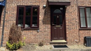 A two-story brick building with a central entrance, a satellite dish, and a small garden area. - Buckland Mews - sleeps 4 guests  in 2 bedrooms (Abingdon)