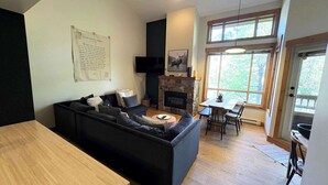 Un salon moderne avec un canapé, une cheminée, une table à manger et un téléviseur.