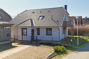 A single-story house with a tiled roof, a front porch, and a small garden area. - House Clemens - Apartment Julius: Balcony (Mönchgut)