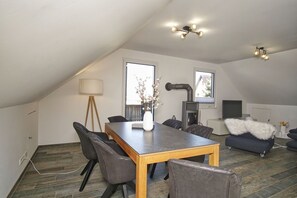 A modern loft with a dining area, a fireplace, and a cozy seating area. - House Clemens - Apartment Julius: Balcony (Mönchgut)