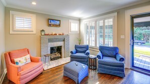 Una sala de estar con chimenea, dos sillones, una mesa de centro y una puerta que da al exterior.