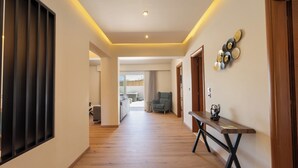 A hallway with wooden flooring, a bench, and a wall-mounted decorative piece. - Two Bedroom Villa with Private Pool (Rhodes)