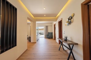 A hallway with wooden flooring, a bench, and a wall-mounted decorative piece. - Two Bedroom Villa with Private Pool (Rhodes)