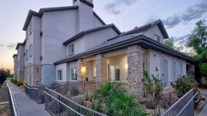 A modern two-story house with a stone facade, a covered porch, and a small garden. - Studio 6 Bakersfield_2 Full Beds | Smoki (Bakersfield)